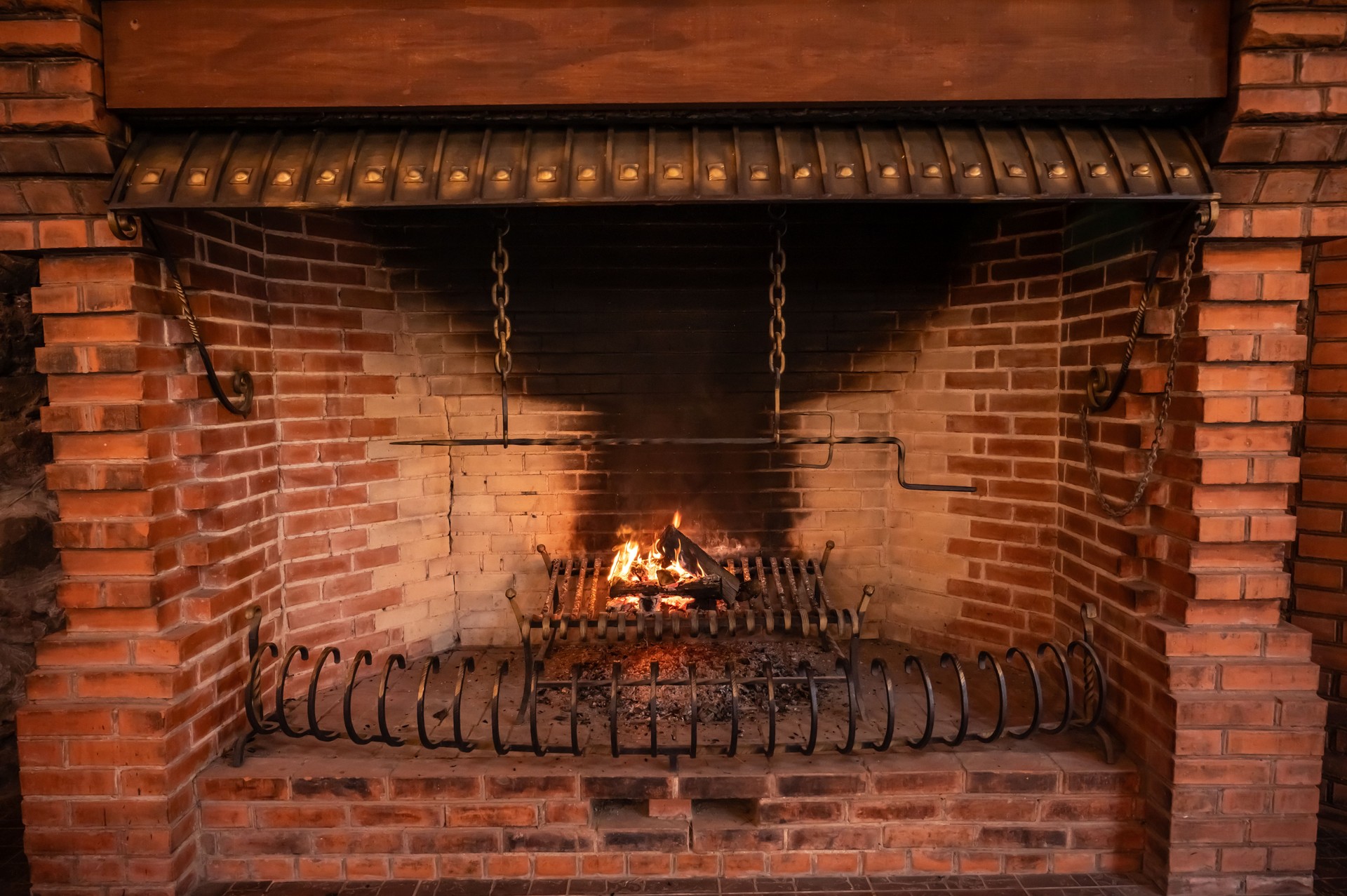 a large old brick fireplace with metal grates and a fire burning in it